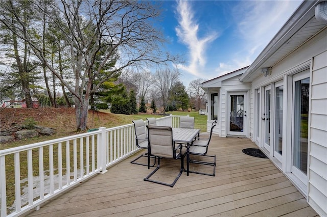 wooden deck featuring outdoor dining area and a lawn