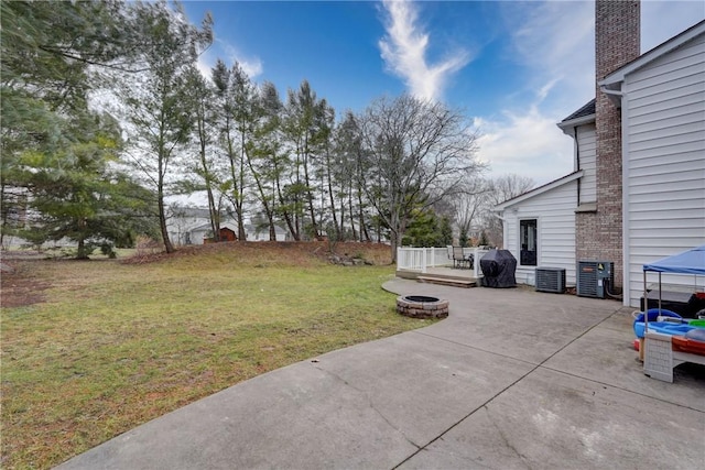 view of yard featuring a fire pit, central AC unit, a deck, and a patio area