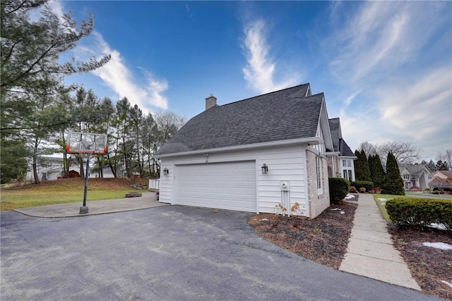 view of side of property with a yard, a chimney, a garage, and a shingled roof