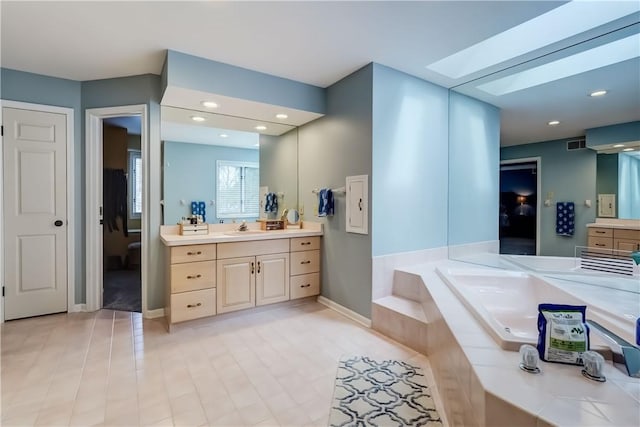 bathroom with visible vents, a garden tub, a skylight, and vanity