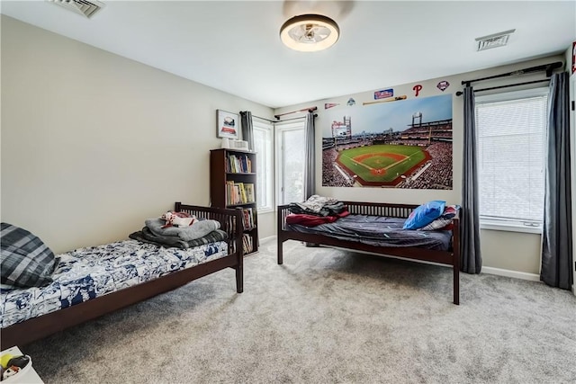 carpeted bedroom featuring visible vents, multiple windows, and baseboards