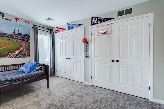 carpeted bedroom featuring visible vents, two closets, and baseboards