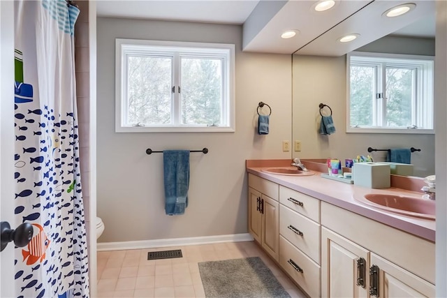 full bath with a sink, visible vents, baseboards, and double vanity