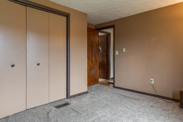 unfurnished bedroom with visible vents, baseboards, carpet floors, a closet, and a textured ceiling