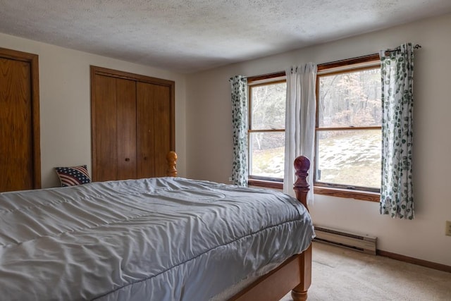 bedroom featuring a textured ceiling, light carpet, baseboards, and a baseboard radiator