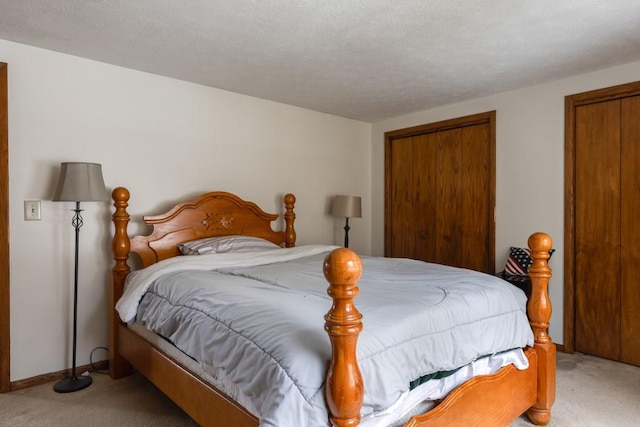 bedroom featuring baseboards, light carpet, and a textured ceiling