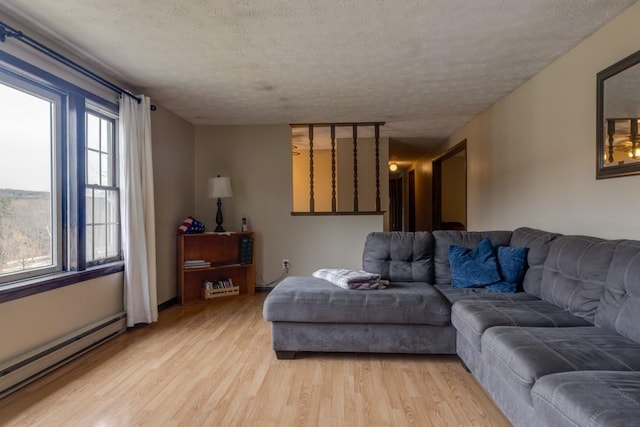 living area featuring a baseboard heating unit, a textured ceiling, and light wood finished floors