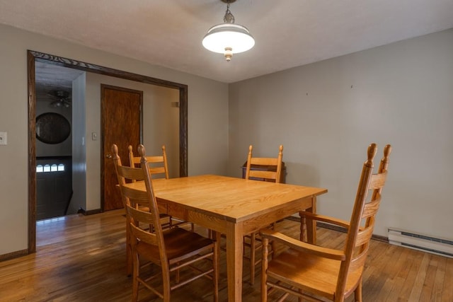 dining area featuring stacked washing maching and dryer, hardwood / wood-style flooring, baseboards, and a baseboard radiator