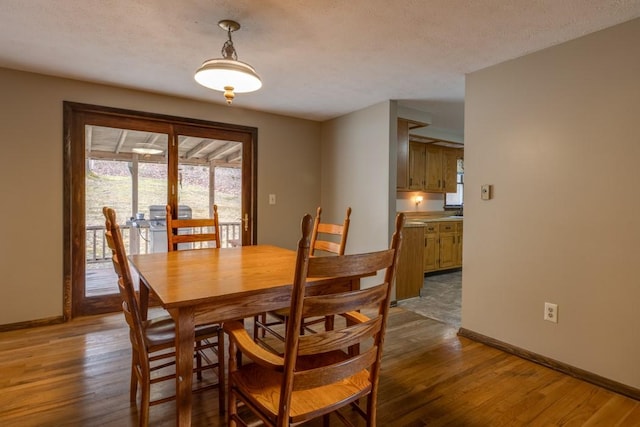 dining room featuring dark wood-style floors, a textured ceiling, and baseboards