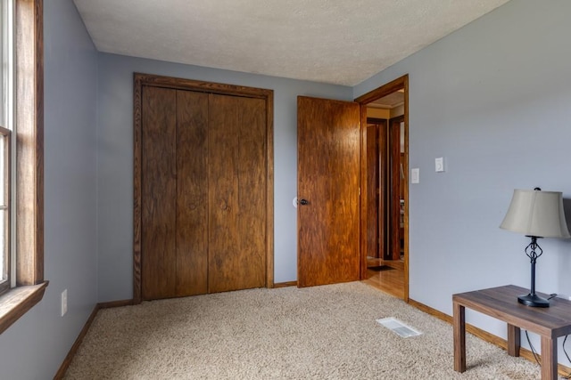 bedroom with a closet, visible vents, baseboards, and carpet