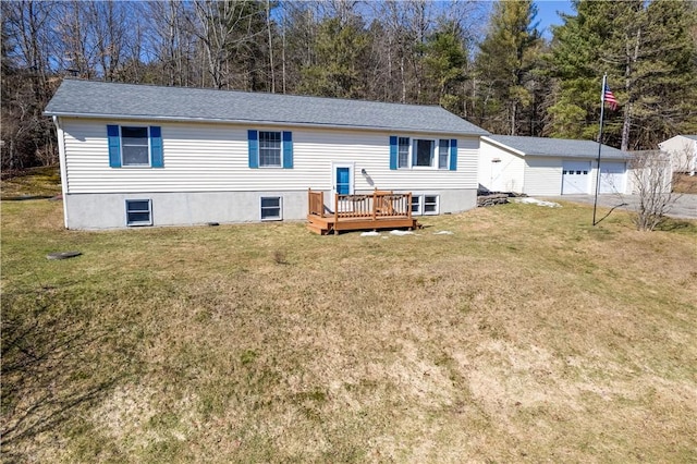 rear view of house featuring a detached garage, an outbuilding, a deck, and a lawn