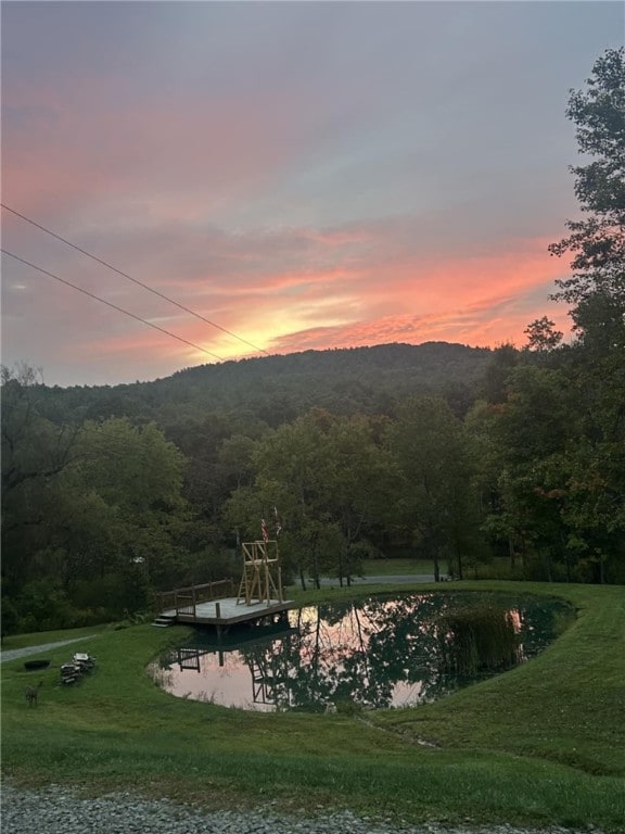 surrounding community with a floating dock, a yard, and a view of trees