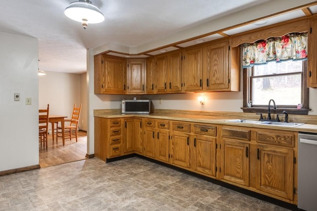 kitchen with a sink, brown cabinets, appliances with stainless steel finishes, and light countertops