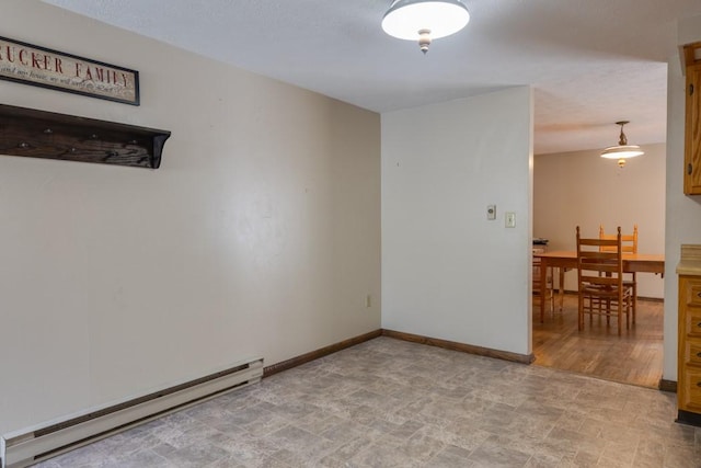 unfurnished room featuring a baseboard heating unit and baseboards