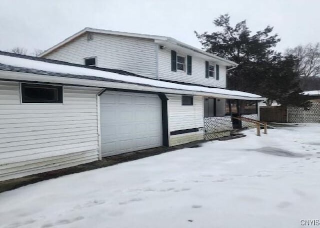 view of snowy exterior featuring a garage and fence