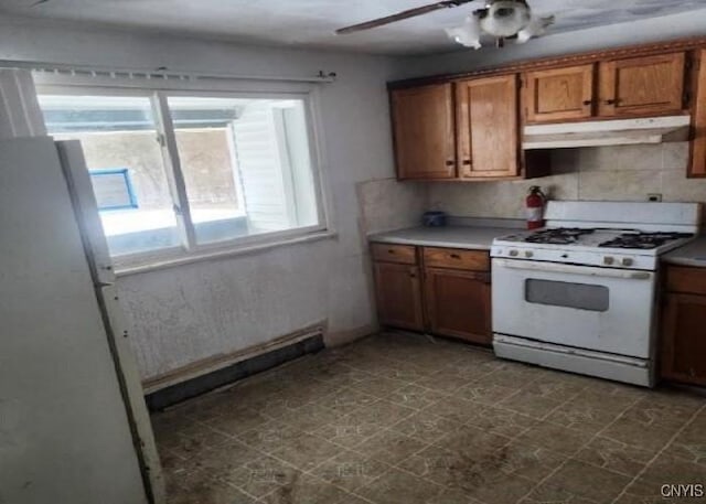 kitchen featuring brown cabinetry, gas range gas stove, light countertops, under cabinet range hood, and backsplash