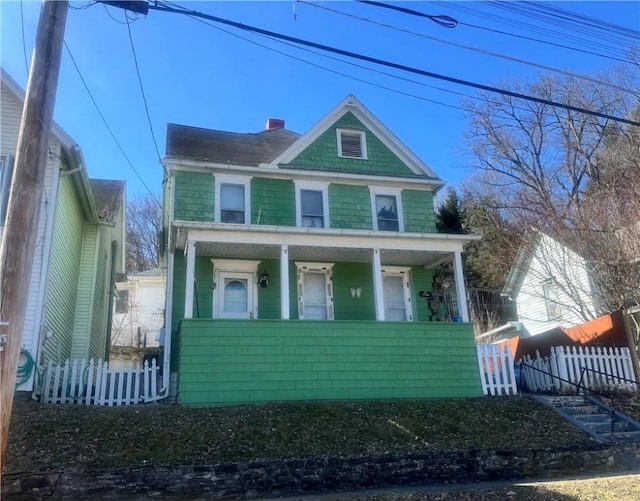 view of front of house featuring a fenced front yard, covered porch, and a chimney