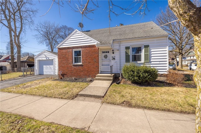 bungalow-style home with brick siding, fence, aphalt driveway, a front yard, and an outdoor structure