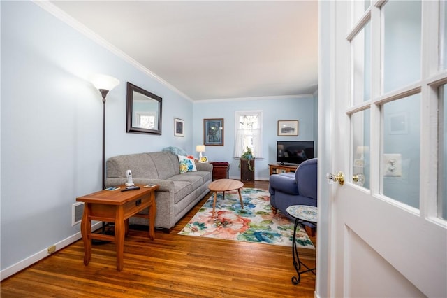 living room featuring ornamental molding, baseboards, and wood finished floors