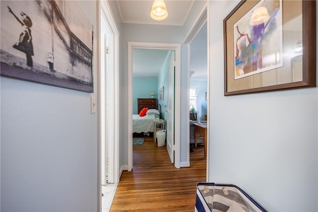 corridor featuring wood finished floors, baseboards, and ornamental molding