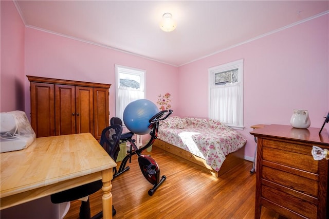 bedroom with baseboards, wood finished floors, and ornamental molding