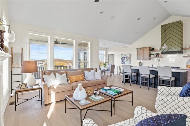 living area with light wood finished floors, visible vents, and high vaulted ceiling