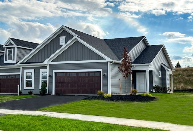 view of front of home with a front lawn, aphalt driveway, board and batten siding, roof with shingles, and an attached garage