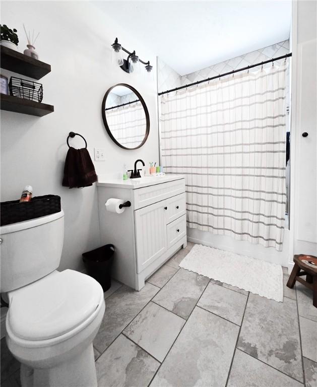 bathroom featuring shower / bath combo with shower curtain, toilet, and vanity