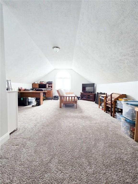 rec room with baseboards, a textured ceiling, carpet flooring, and vaulted ceiling