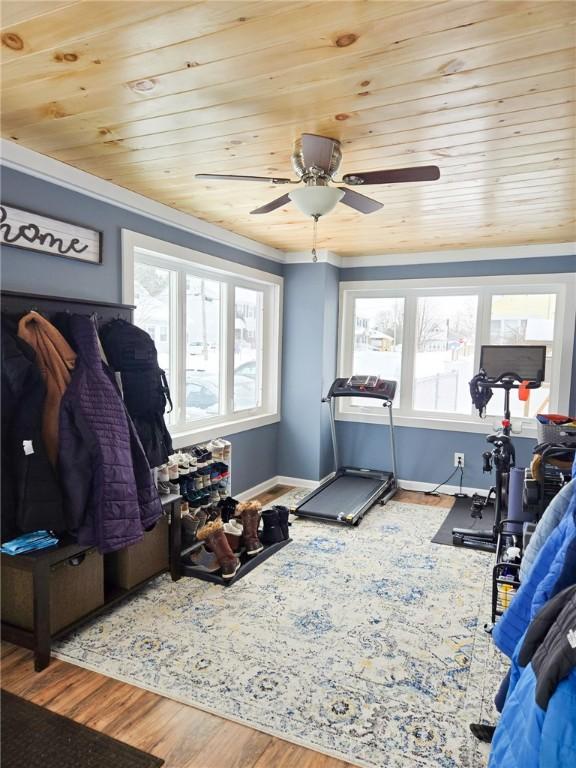 workout area featuring wood finished floors, wooden ceiling, crown molding, baseboards, and ceiling fan