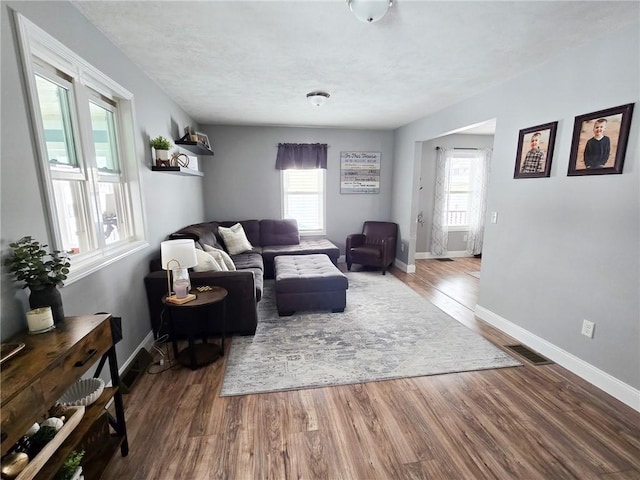 living room featuring visible vents, baseboards, and wood finished floors