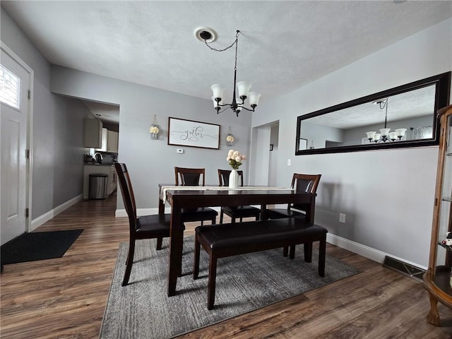 dining space featuring dark wood-style floors, baseboards, and a chandelier