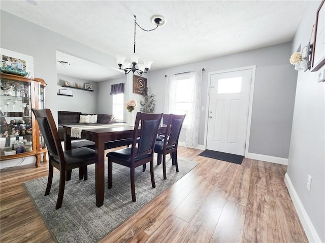 dining area featuring a chandelier, baseboards, and wood finished floors