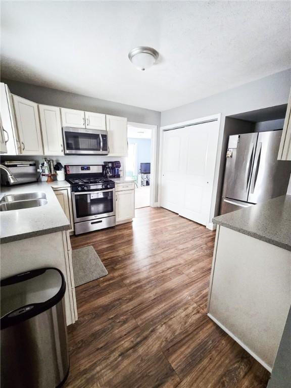 kitchen with white cabinetry, dark wood-style floors, appliances with stainless steel finishes, and a sink