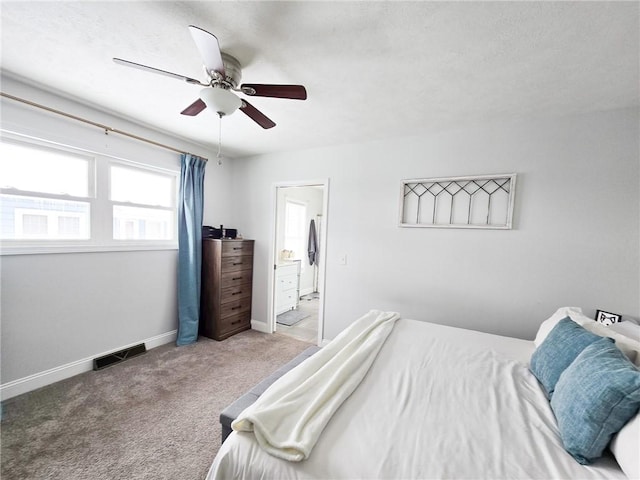 carpeted bedroom featuring visible vents, connected bathroom, a ceiling fan, and baseboards