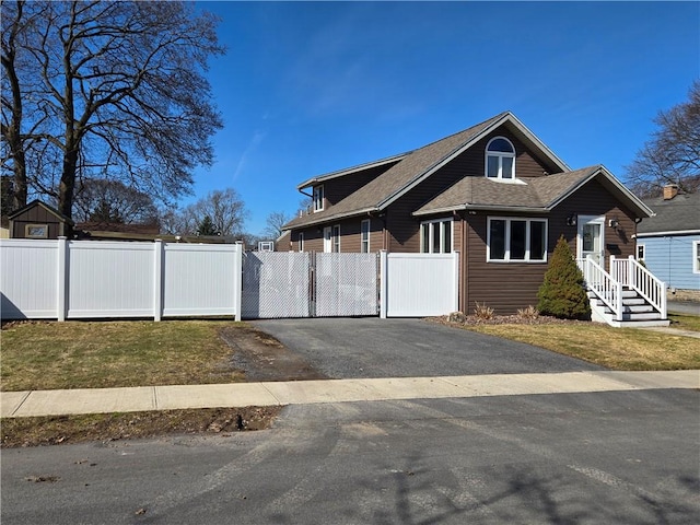 view of property exterior with aphalt driveway, fence, roof with shingles, and a gate