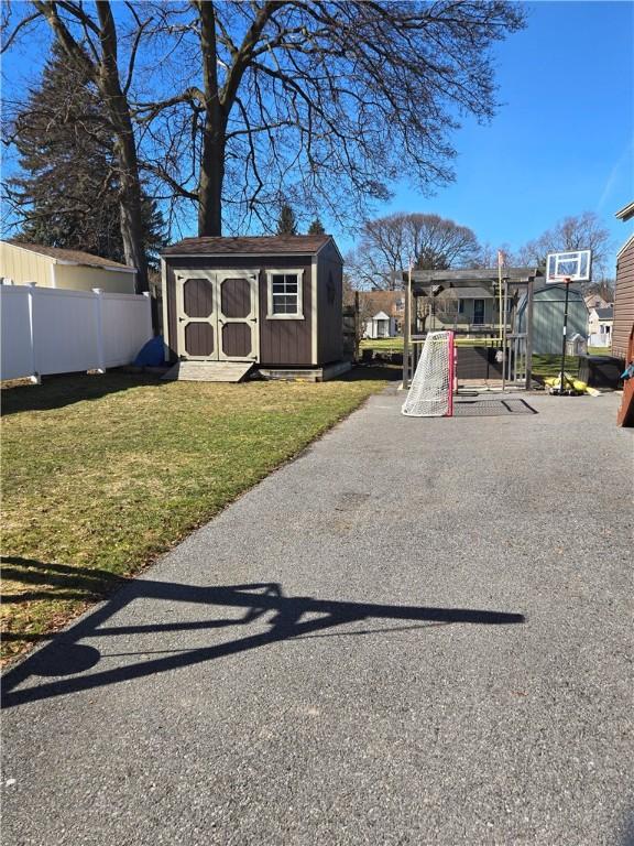 view of play area with a storage unit, an outbuilding, a yard, and fence