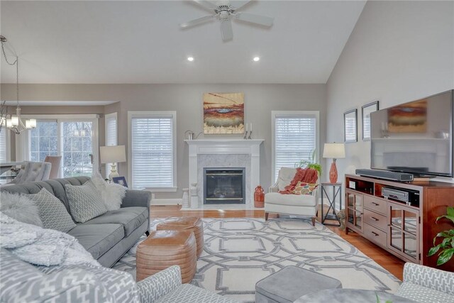 living area with plenty of natural light, light wood-style flooring, a tile fireplace, and vaulted ceiling