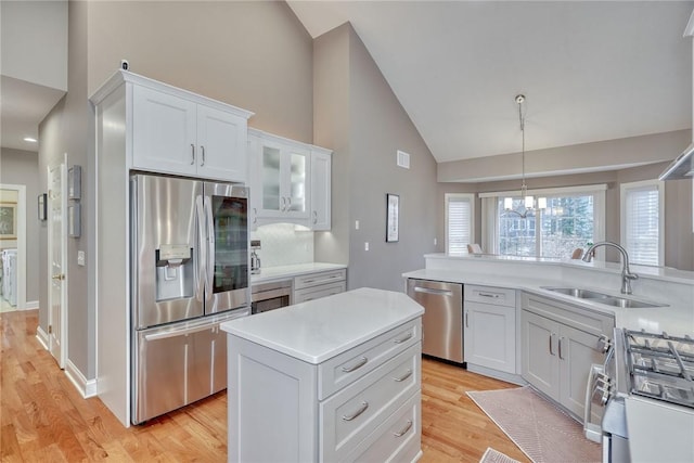 kitchen featuring light countertops, stainless steel appliances, light wood-style floors, white cabinetry, and a sink