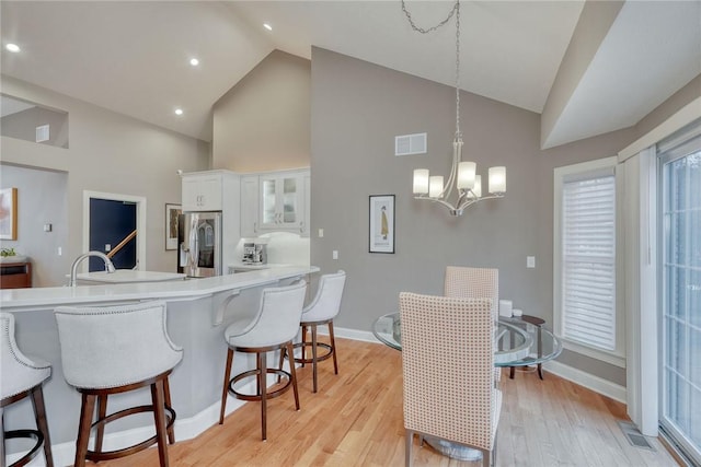 kitchen with visible vents, stainless steel fridge with ice dispenser, white cabinets, a kitchen bar, and light wood-type flooring