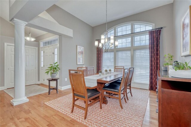 dining space with a notable chandelier, decorative columns, and light wood finished floors