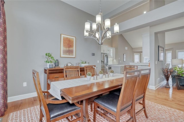 dining space featuring a notable chandelier, light wood-style flooring, high vaulted ceiling, and baseboards