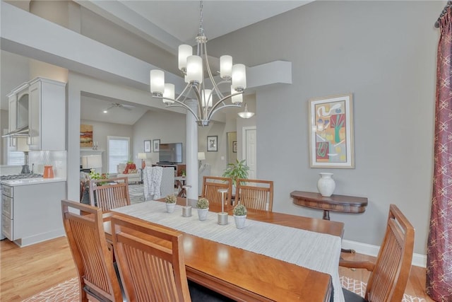 dining space with an inviting chandelier, light wood-style flooring, baseboards, and lofted ceiling