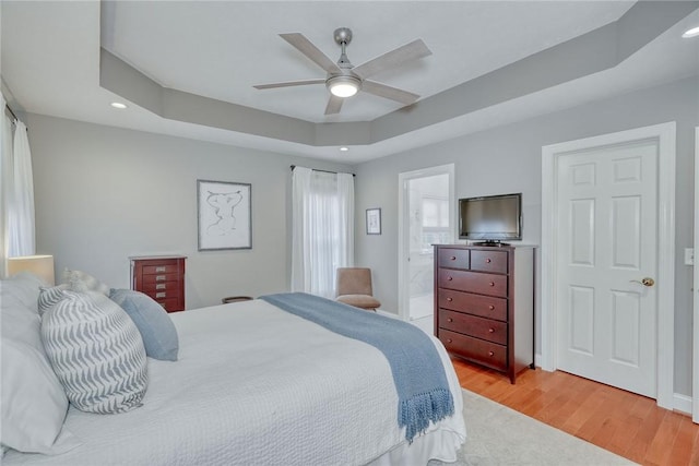 bedroom with light wood-type flooring, a tray ceiling, baseboards, and recessed lighting