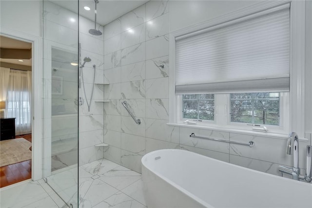 bathroom with a freestanding bath, tile walls, marble finish floor, and tiled shower