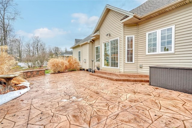 rear view of property featuring entry steps, a patio area, and roof with shingles