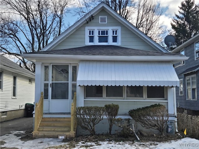 bungalow with a sunroom, roof with shingles, and entry steps