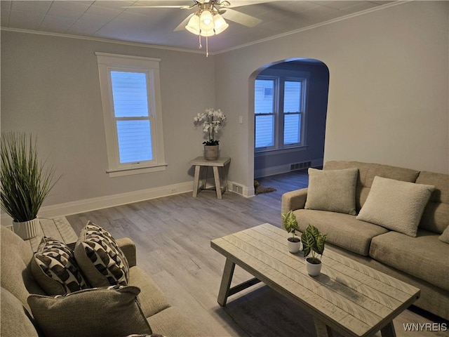 living room featuring visible vents, wood finished floors, arched walkways, crown molding, and baseboards