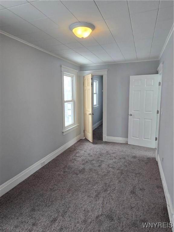 unfurnished bedroom featuring baseboards, crown molding, and carpet