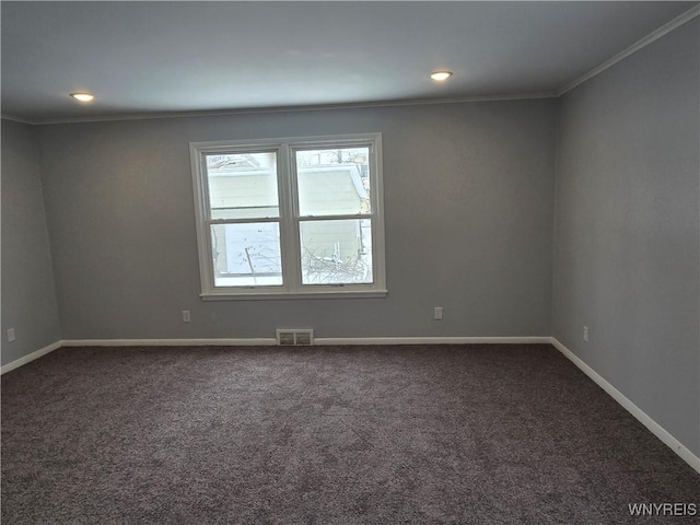 spare room featuring baseboards, visible vents, and dark carpet